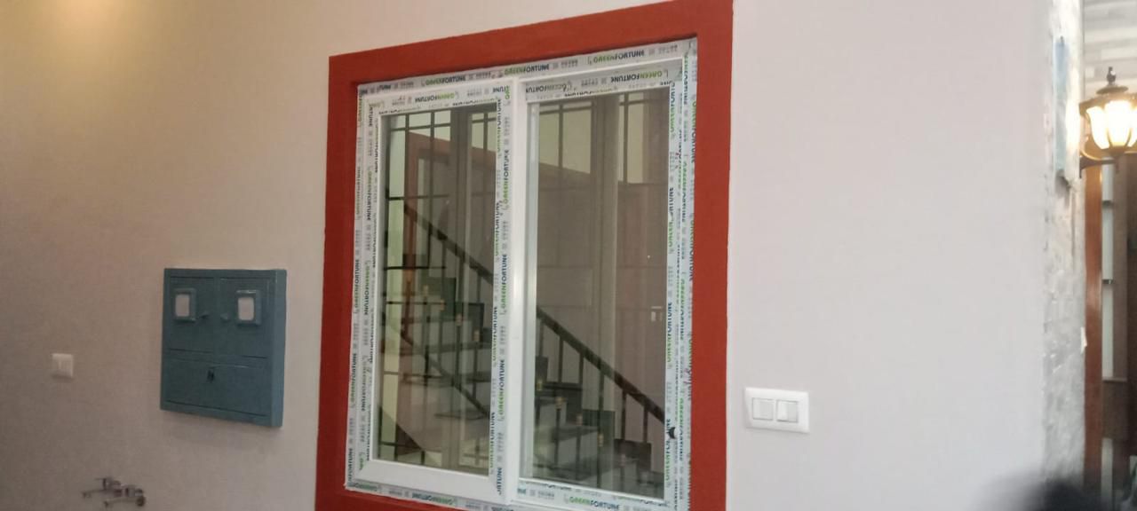 Two-Track uPVC Sliding Window in Red Accent Border Overlooking Staircase