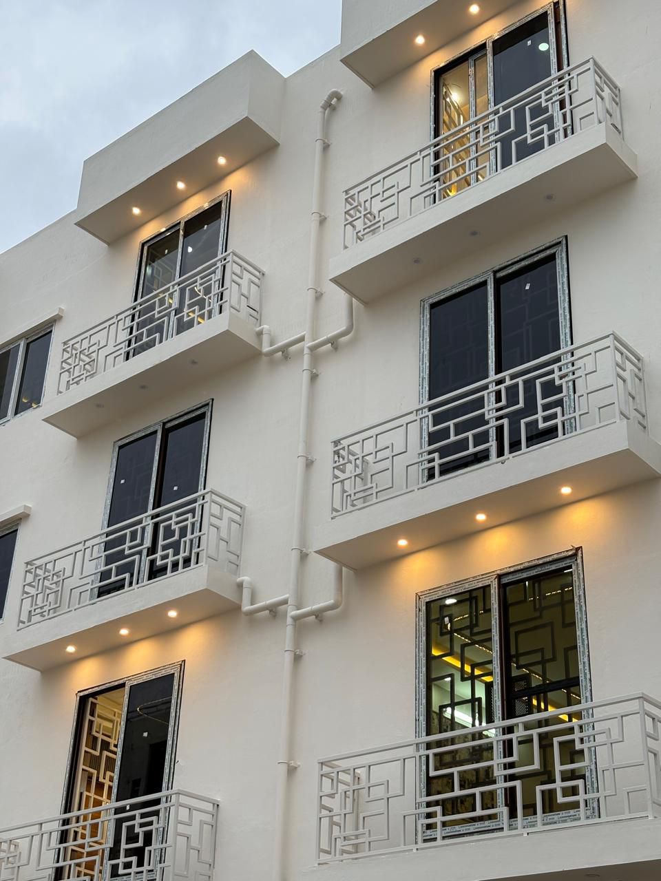Contemporary White Facade with Geometric Balconies and Warm Architectural Downlights